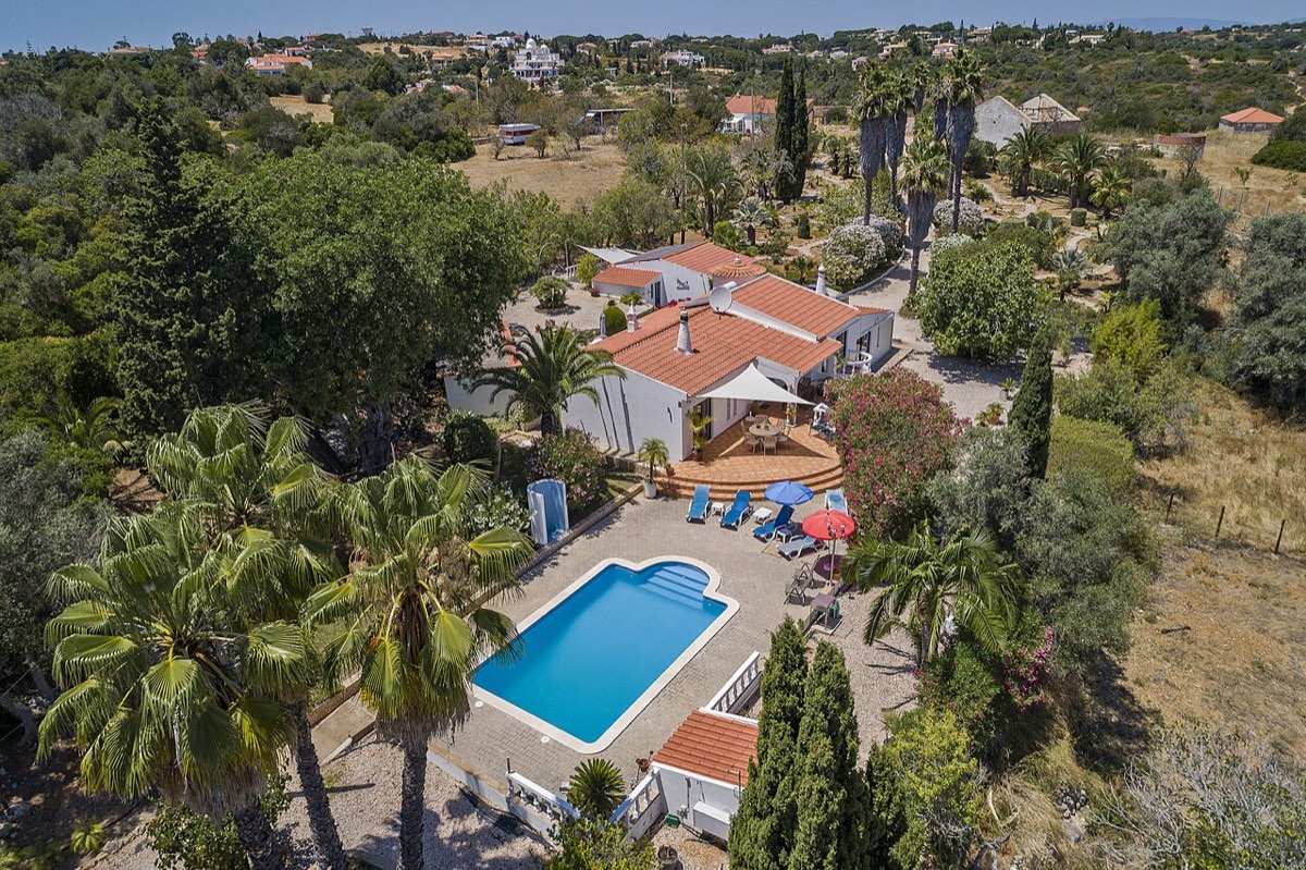 Vista aérea de uma moradia de férias no Algarve com piscina privada, palmeiras e jardim