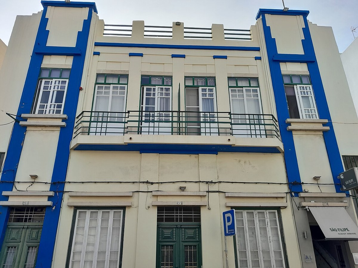 Fachada de uma guest house em Faro, edifício branco com molduras azuis e varanda corrida
