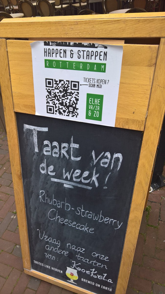 Quadro de rua de um café com um cartaz com código QR por cima do menu escrito a giz