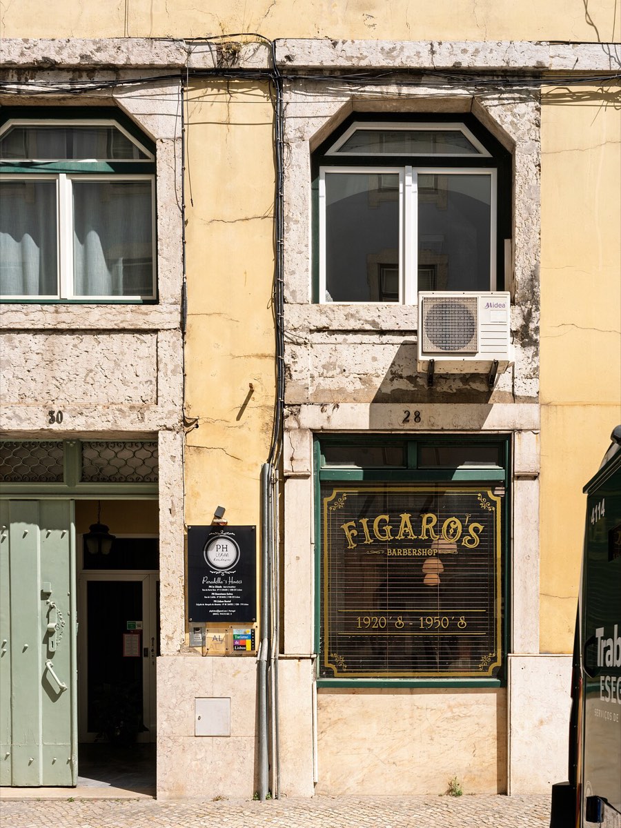 Fachada da Figaro's Barbershop na Baixa de Lisboa, com montra verde e letras douradas num prédio antigo amarelo