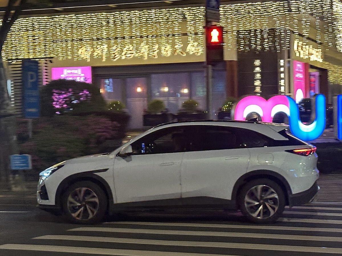 SUV elétrico Arcfox Alpha T5 branco a atravessar uma rua à noite